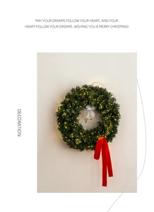 Christmas wreath with warm LED lights and a long red ribbon against a white wall