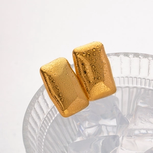 Macro shot of 18K gold rectangular earrings with water drops on ice background