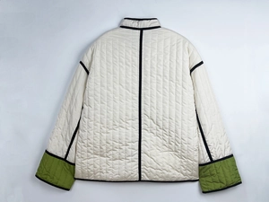 Detail view of the contrast color quilted jacket featuring green sleeves and ivory back