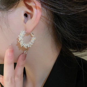 Close-up of silver C-shaped hoop earrings with baguette-cut zircons worn by a model