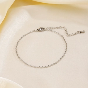 Bracelet de cheville en acier argenté élégant sur fond de soie beige douce