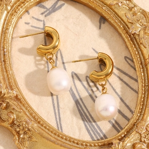 Close-up of vintage 18K gold plated stainless steel pearl earrings on relief frame
