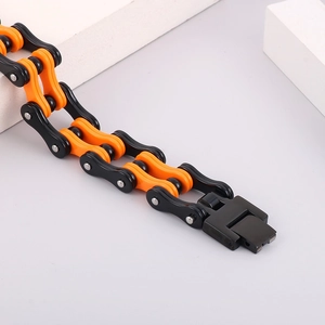 Vista dettagliata del bracciale a catena da moto nero e arancione su cubi bianchi