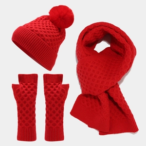 Detailed view of red knitted winter set including pompom beanie scarf and arm warmers