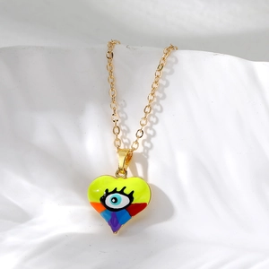 Detail of a gold-plated heart pendant featuring a colorful enamel evil eye design