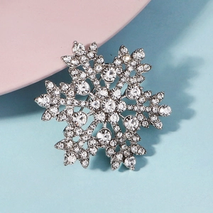 Macro detail of snowflake brooch with silver metal base and sparkling rhinestones