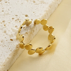 Bague ouverte irrégulière à pois en finition or 18k sur une pierre blanche texturée