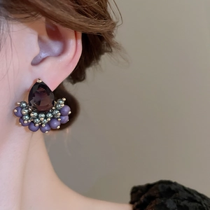 Detail of vintage teardrop purple zircon stud earring on ear with gold fan-shaped beads