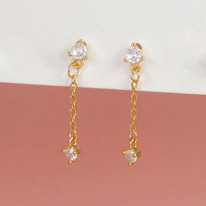 Detail of elegant gold drop earrings with chains and sparkling round clear crystals
