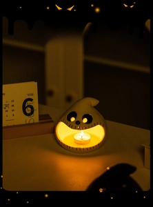 Close-up of white ceramic ghost candle holder with flickering warm tea light inside