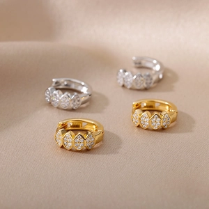 Macro detail of gold and silver C-shaped hoop earrings with zircon pave setting