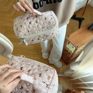 Close-up of quilted pink makeup bag featuring cartoon bear print and metal zipper detail