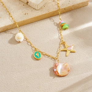Collier plaqué or avec breloques d'étoiles de mer et coquillages sur fond de sable