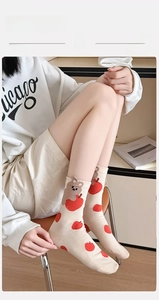 Detail of cute cotton crew socks featuring red apple and brown bear patterns