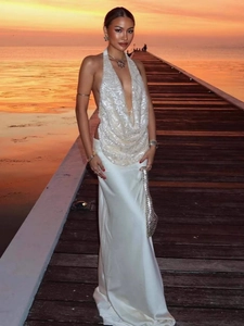 Détail d'une robe dos nu en satin blanc avec paillettes sur un quai au coucher du soleil