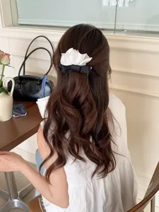Barrette élégante en satin blanc avec nœud papillon sur une queue de cheval haute au café