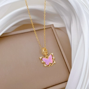 Gros plan du pendentif papillon rose sur chaîne dorée avec soie blanche et boîte à bijoux