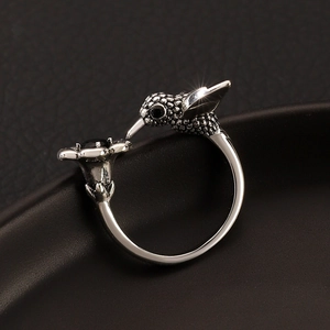 Macro detail of silver hummingbird ring with black gemstones on a dark matte surface