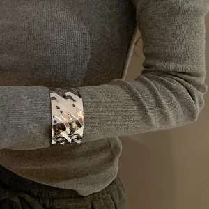 Minimalist wide silver metal cuff bracelet featuring irregular crumpled texture design