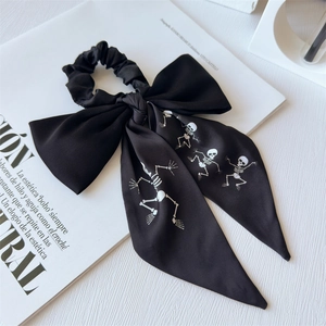 Detail of black satin bow scrunchie with white dancing skeleton prints for ponytail