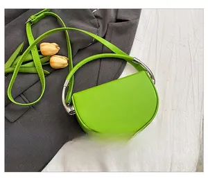 Detailed back view of a green crescent saddle bag with silver metal handle on a grey blazer