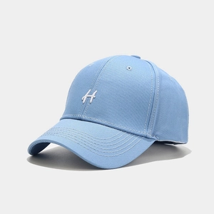 Dettaglio del ricamo della lettera H bianca su un cappellino da baseball in cotone azzurro