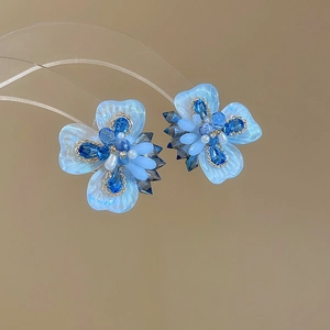 Detailed macro view of light blue crystal flower stud earrings with pearl accents