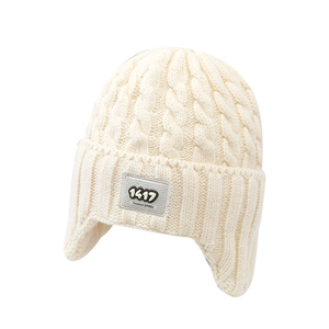 Off-white cable knit trapper hat for kids featuring protective earflaps and a fabric patch