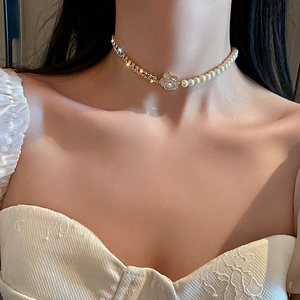 Détail d'un collier floral doré avec perles et strass porté par un mannequin élégant