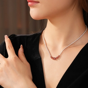 Detail of silver chain necklace with red oval gemstones on a model wearing black