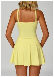 Detalle de tirantes cruzados y dobladillo plisado de un vestido de tenis amarillo