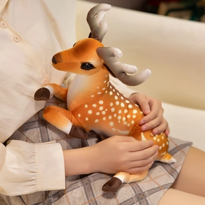 Plush sika deer doll with white spots and soft antlers held in a cozy home setting
