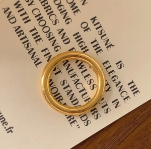 Top-down view of polished minimalist gold-tone stackable silver ring on a display card