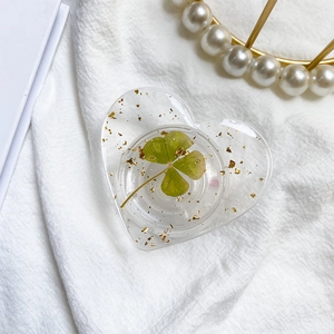 Macro detail of heart phone grip featuring a real four leaf clover and golden foil accents