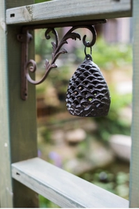 Detailed macro view of vintage pinecone cast iron bell with bronze finish and rustic bracket