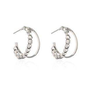 Close-up of silver hoop earrings with geometric faceted beads and polished inner ring