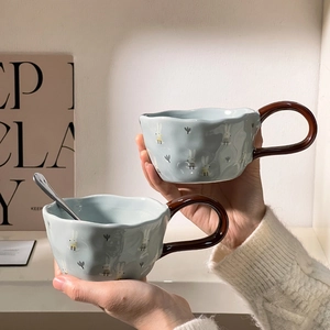 Detail of two light blue ceramic bear mugs with white rabbits and brown handles