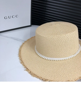 Detailed macro view of French straw hat with elegant pearl trim and frayed edge finish