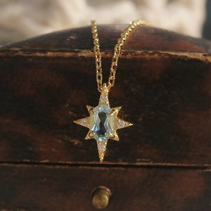 Close-up of starburst pendant with oval blue topaz and sparkling diamonds on gold chain
