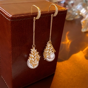 Détail macro de boucles d'oreilles perles dorées avec pompons en zircon sur cuir