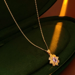 Detail of vintage gold necklace with purple gemstone pendant on green velvet box