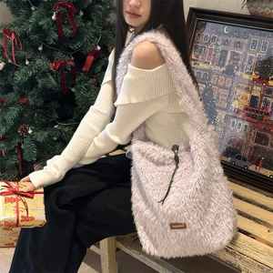 Detail of plush lavender faux fur shoulder bag with leather logo tag and cozy texture