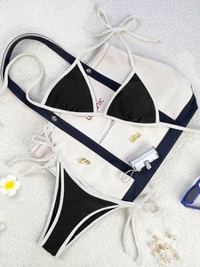 Flat lay of black and white contrast bikini set with tie sides on white canvas bag
