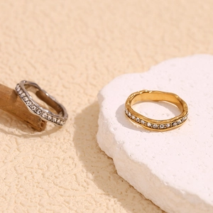 Detail of 18K gold and silver plated wave rings with crystals on natural stone background