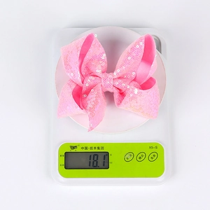 Detailed view of a 5-inch pink sequined bow hair clip weighing 18.1 grams on a scale