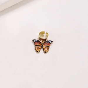 Close-up of golden metal hair ring with a detailed orange and black butterfly pendant