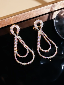 Close-up of luxury long teardrop rhinestone earrings in gold with colorful AB crystals