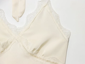 Detail of V-neck lace trim and adjustable ties on cream satin camisole top