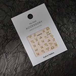 Dettaglio macro di ciondoli per nail art zodiaco dorati con piccole perle