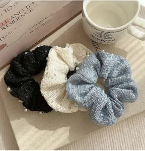 Close-up of three tweed hair scrunchies with white pearls and sequins on a classic book